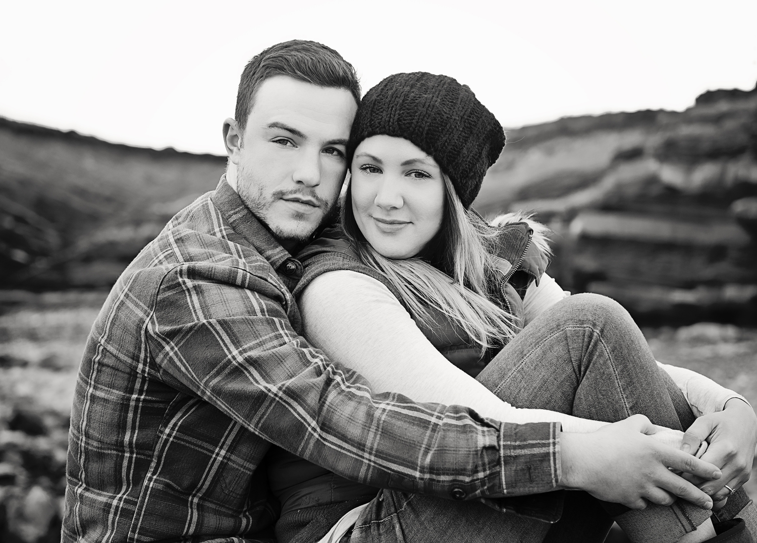 Black-and-white posed portrait of a couple hugging on the Somerset coastline, captured by a pet and family photographer.